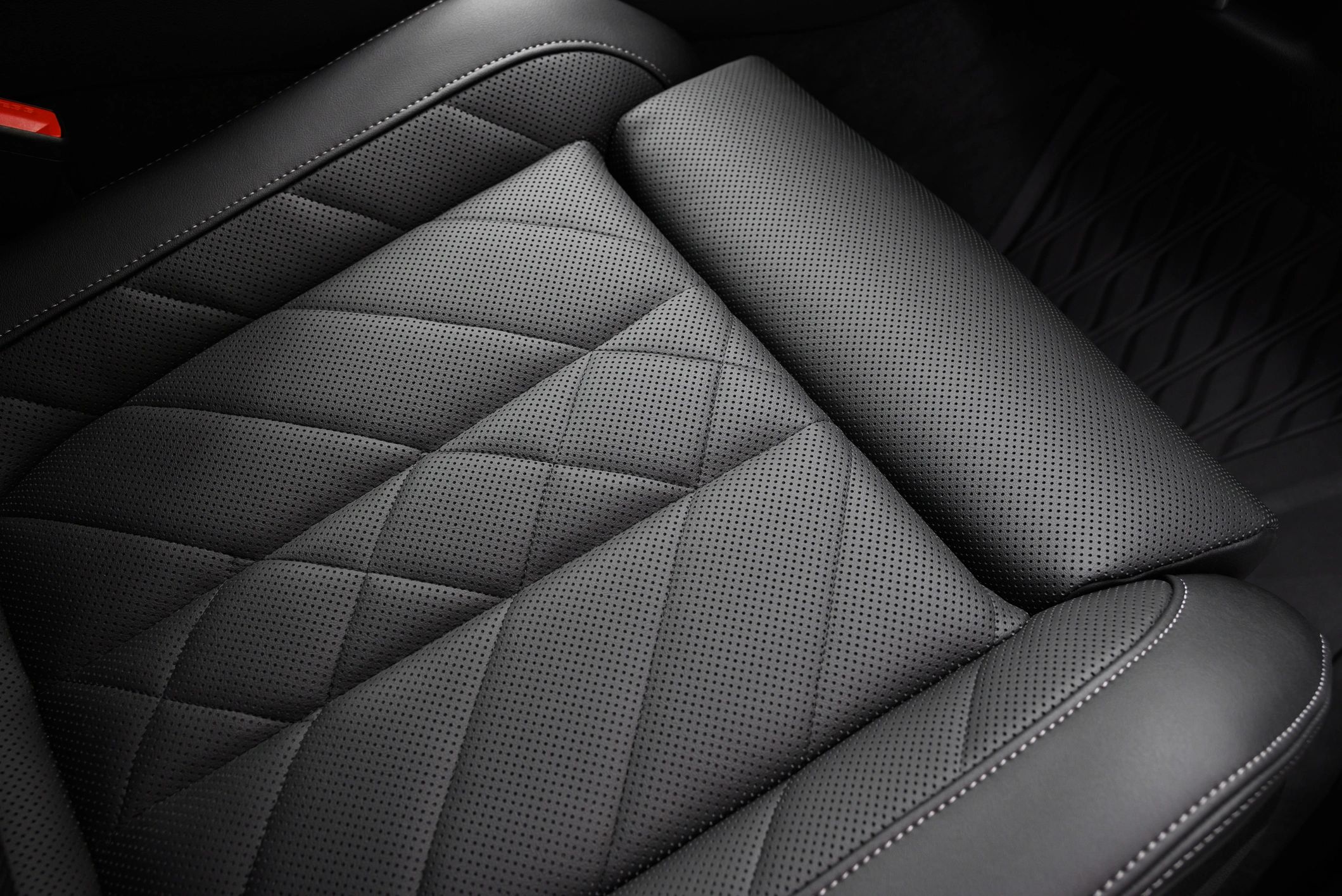 Close-up of black perforated leather seat upholstery with stitching